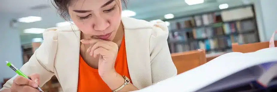 Moça pensando e lendo em biblioteca