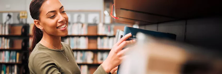 Moça escolhendo livro em biblioteca