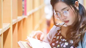 Moça lendo livro em biblioteca