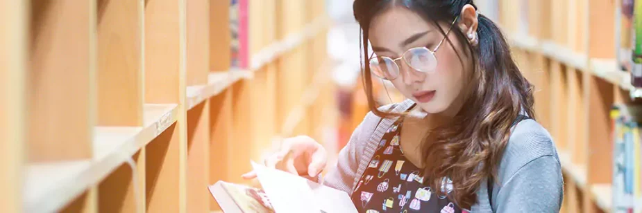Moça lendo livro em biblioteca