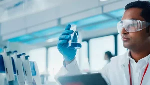 homem em laboratório observando componente azul em recipiente