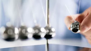 Homem segurando pêndulo de metal