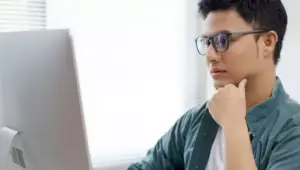 rapaz concentrado lendo em computador