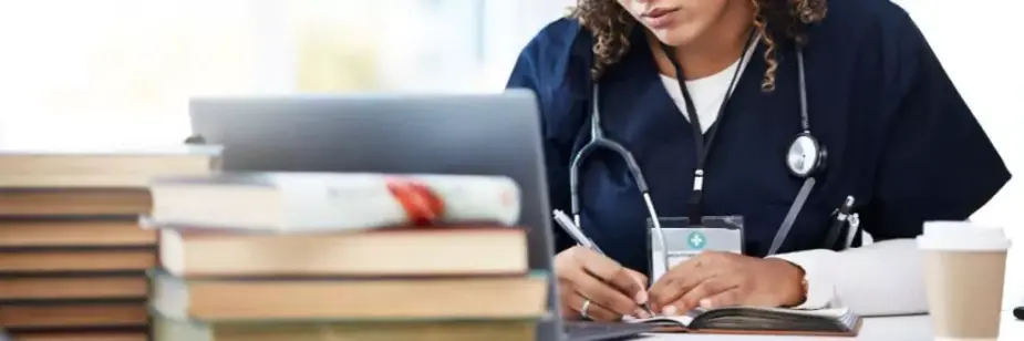 médica estudando com computador e livros