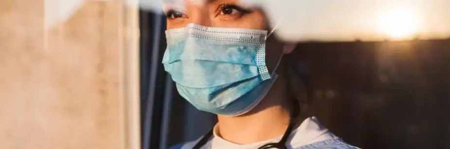 médica olhando para o sol poente por janela